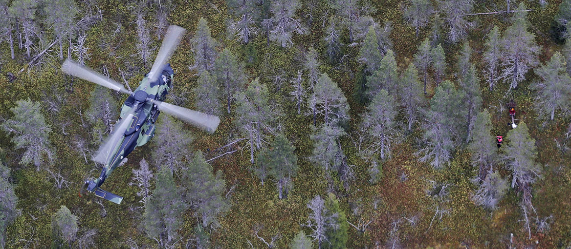 Helikopterit lentävät metsän yllä etsintätehtävässä.
