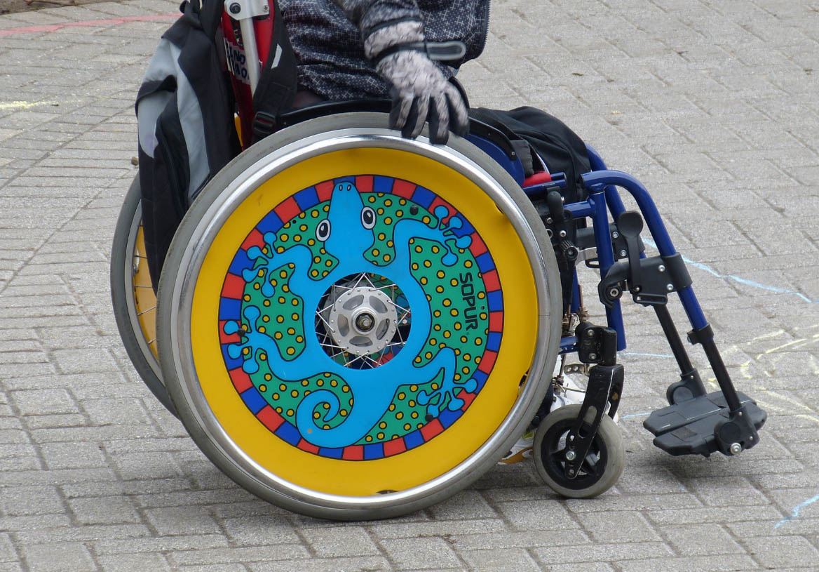 Kuvituskuva: värikäs pyörätuoli jalkakäytävällä.