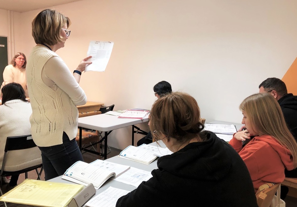 Ryhmä ihmisiä opiskelee suomen kieltä luokassa opettajan johdolla.