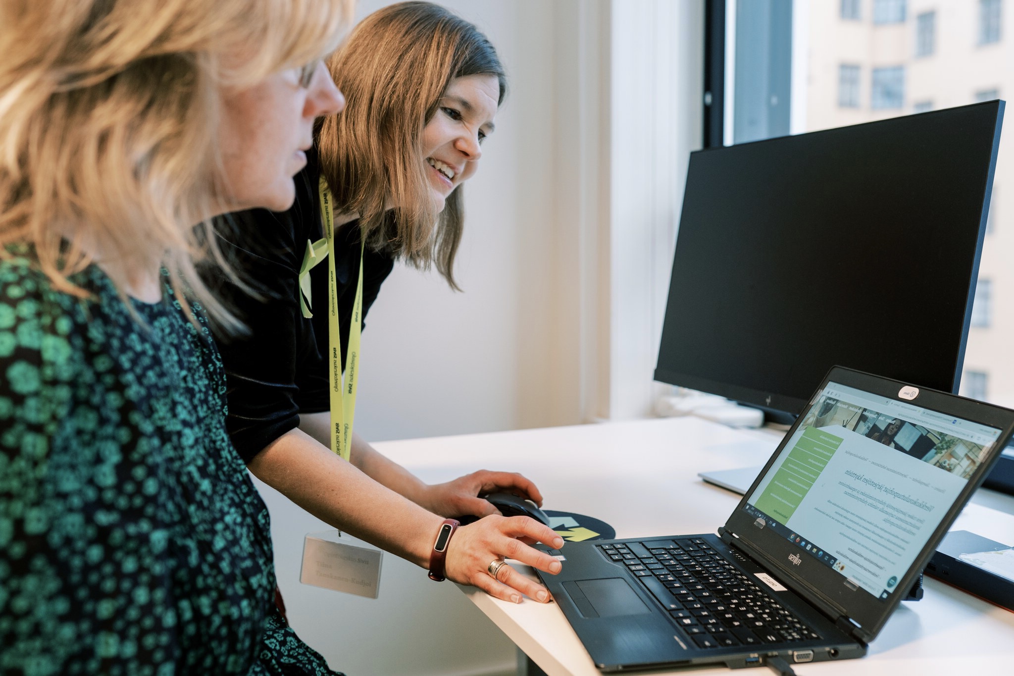 Kouluttaja opastaa opiskelijaa tietokoneen käytössä.