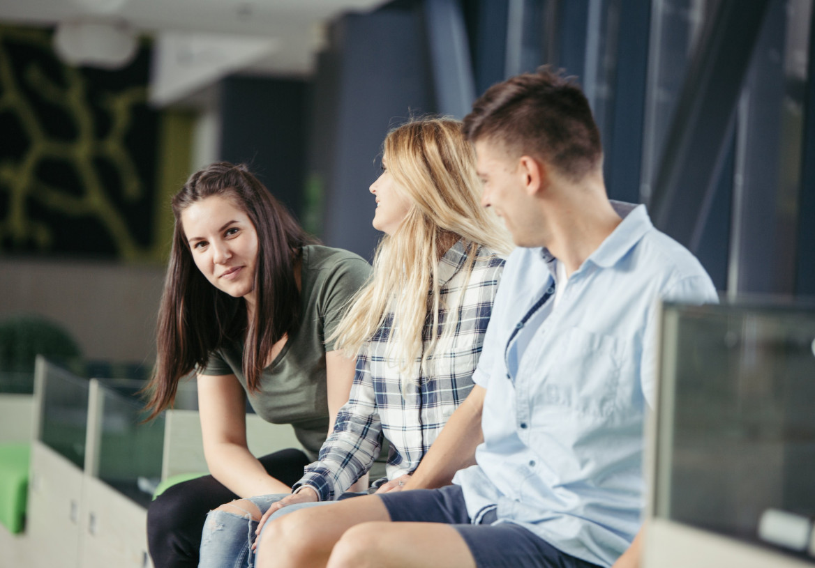 Kolme nuorta juttelee sisätiloissa.