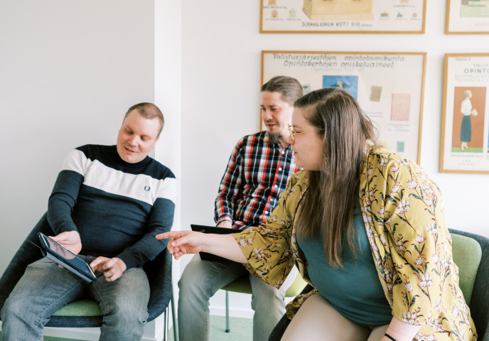 Kolme henkilöä tutkii tablettia.