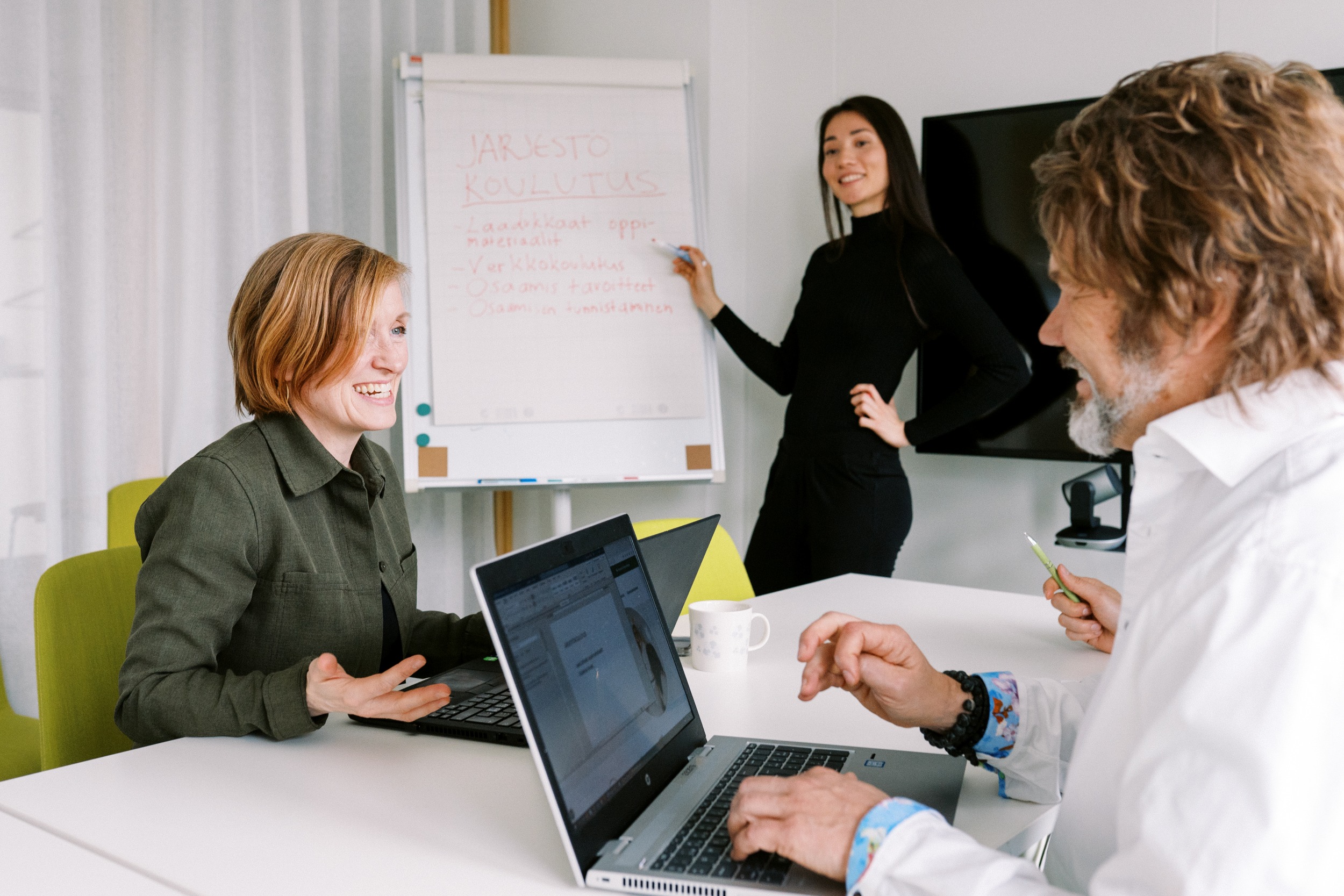 Kolme henkilöä työskentelee neuvotteluhuoneessa.