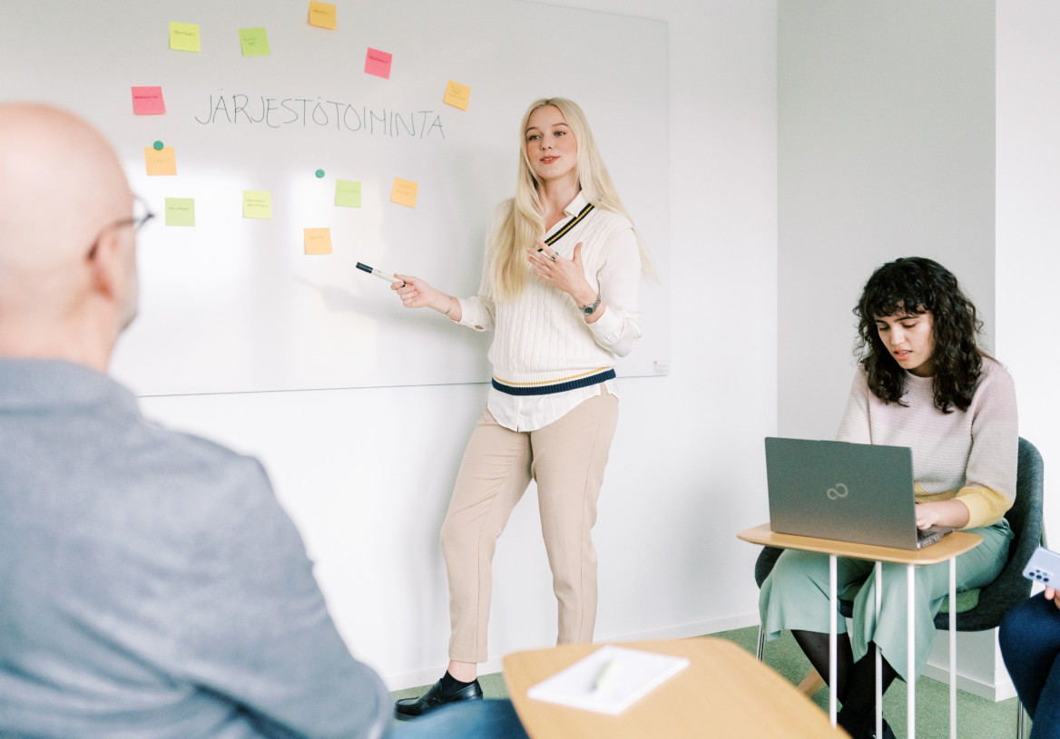 Neljä henkilöä työskentelee neuvotteluhuoneessa.