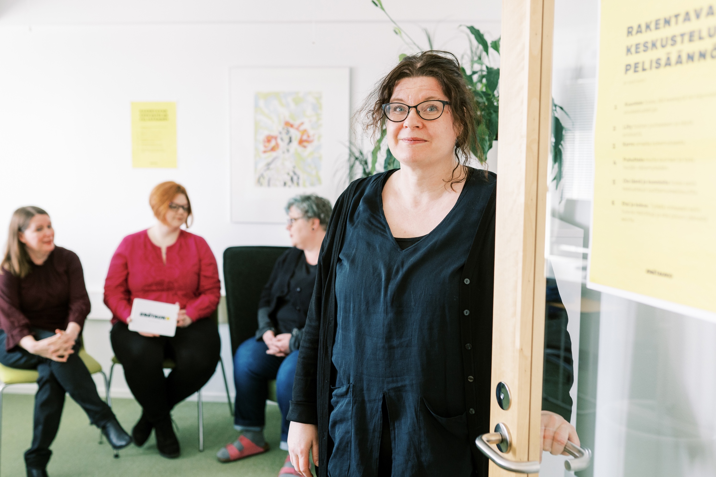 Marion Fields seisoo neuvotteluhuoneen ovella vastaanottamassa keskustelijoita.