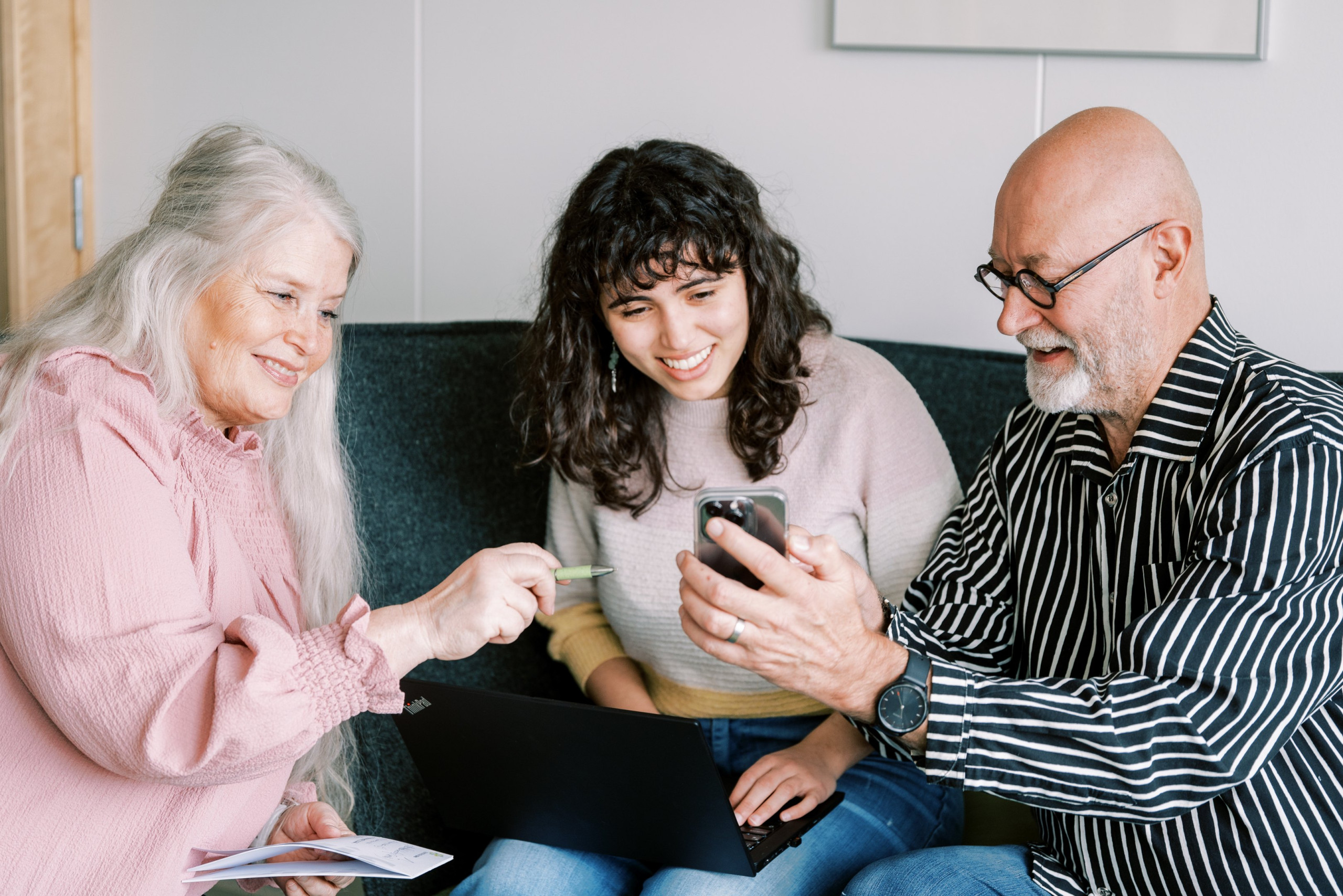 Kolme henkilöä tutkii puhelinta.