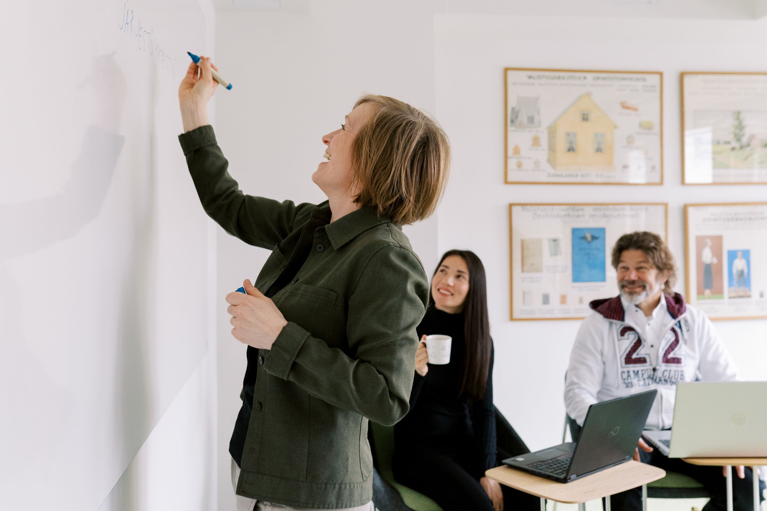 Kolme henkilöä työskentelee yhdessä neuvotteluhuoneessa.