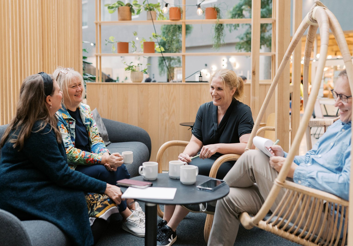 Neljä henkilöä keskustelee sisätiloissa.