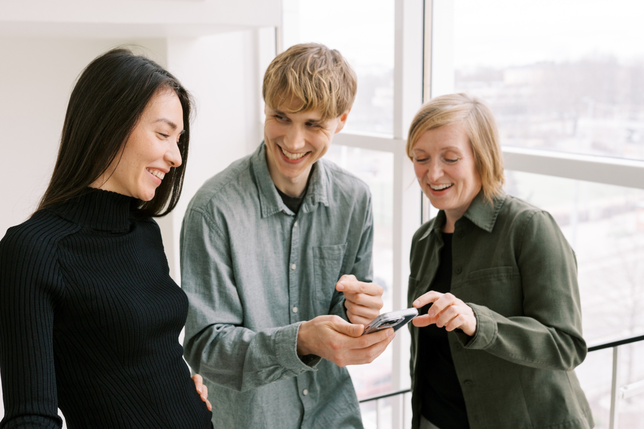 Kolme henkilöä tutkii yhdessä puhelinta.