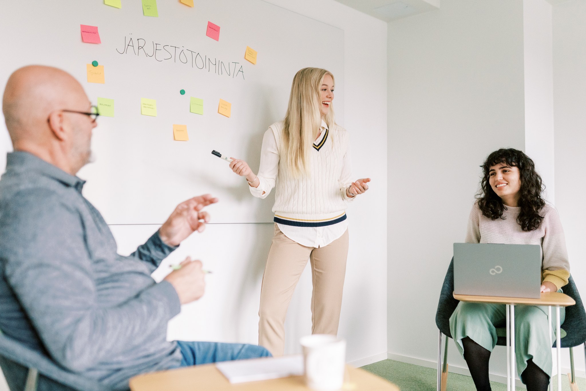 Kolme henkilöä työskentelee neuvotteluhuoneessa.