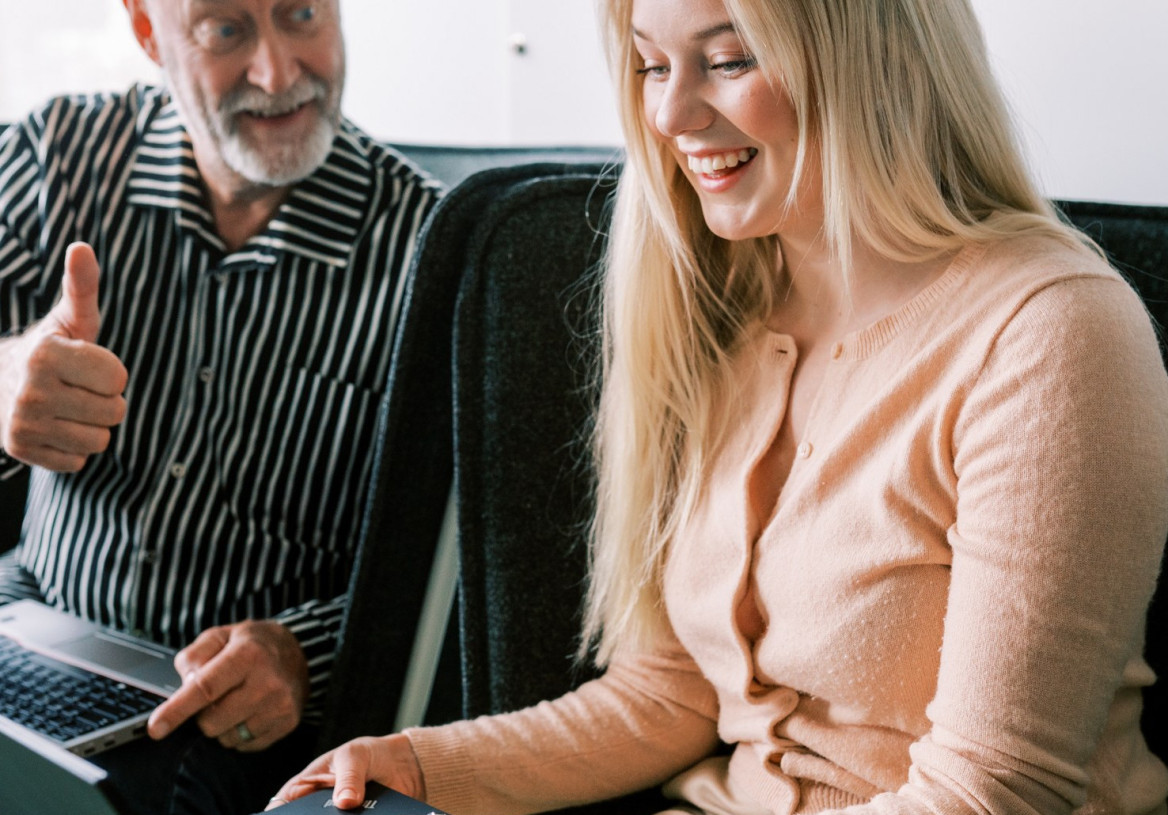Kaksi henkilöä työskentelee yhdessä tietokoneen kanssa sohvalla.